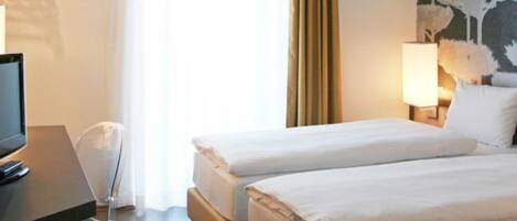 Ein Hotelzimmer mit zwei Betten, einem Schreibtisch, einem Stuhl, einem Fernseher, einer Lampe und einem Bild an der Wand.