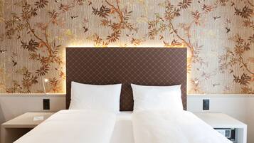 Una habitación de hotel con una cama, dos mesitas de noche y una pared decorada con un estampado floral.