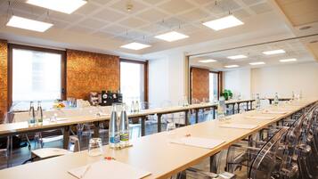 Un salón de conferencias con mesas largas, sillas y una pared con diseño.