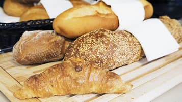 A variety of breads and pastries on a wooden cutting board.