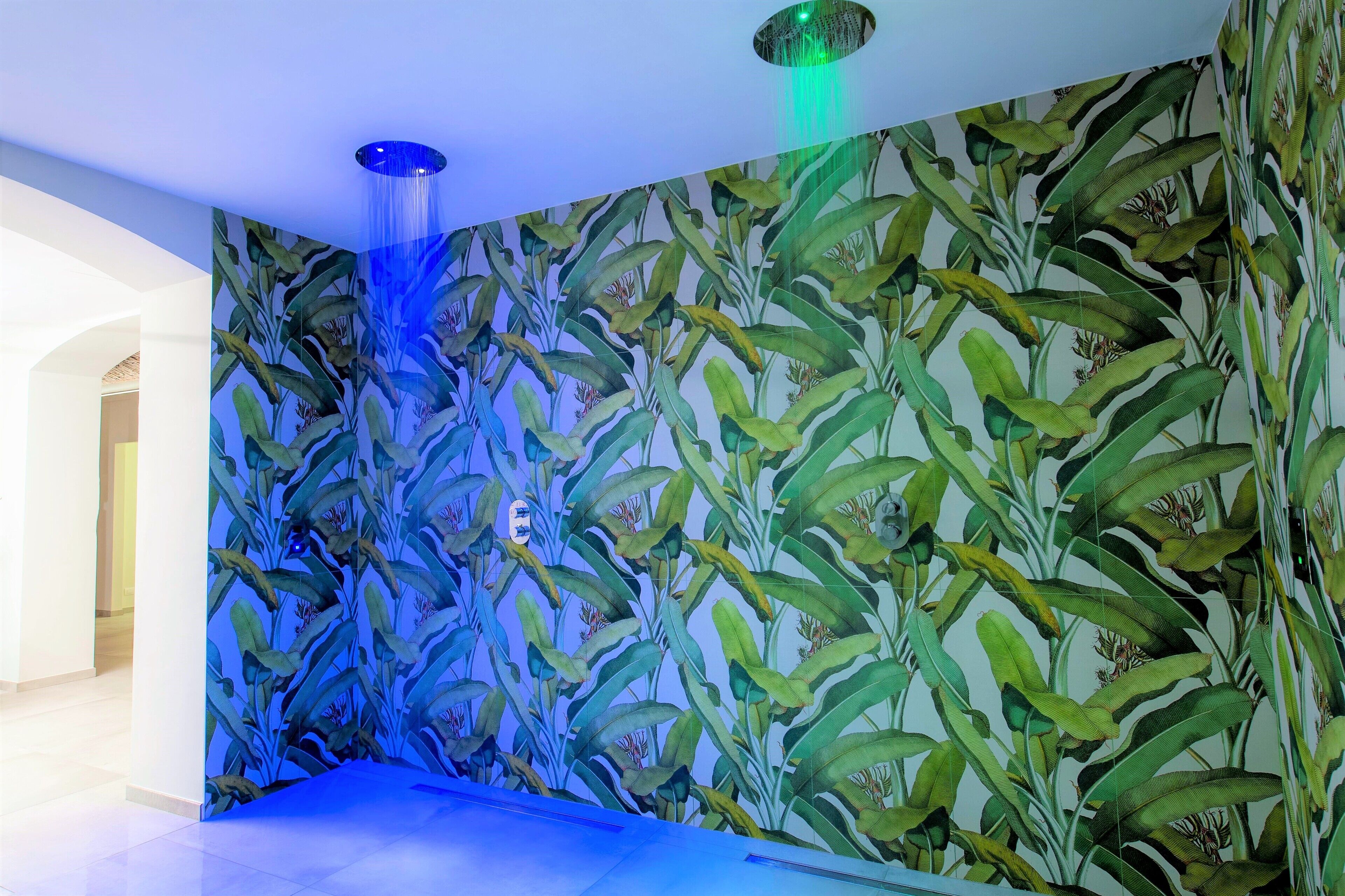 Una habitación con un amplio mural de follaje tropical y una fuente iluminada en azul.