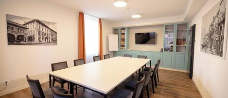A conference room with a long table and chairs, a whiteboard, and a television on the wall.