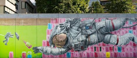 A mural of an astronaut on a basketball court with cans of paint in the background.
