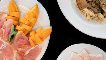 Una mesa con diversos platos, incluyendo pasta, carne en rodajas y verduras.