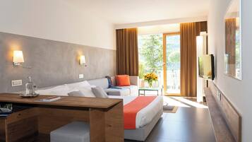 Une chambre d’hôtel avec un lit, un bureau, une télévision et un balcon avec des rideaux.