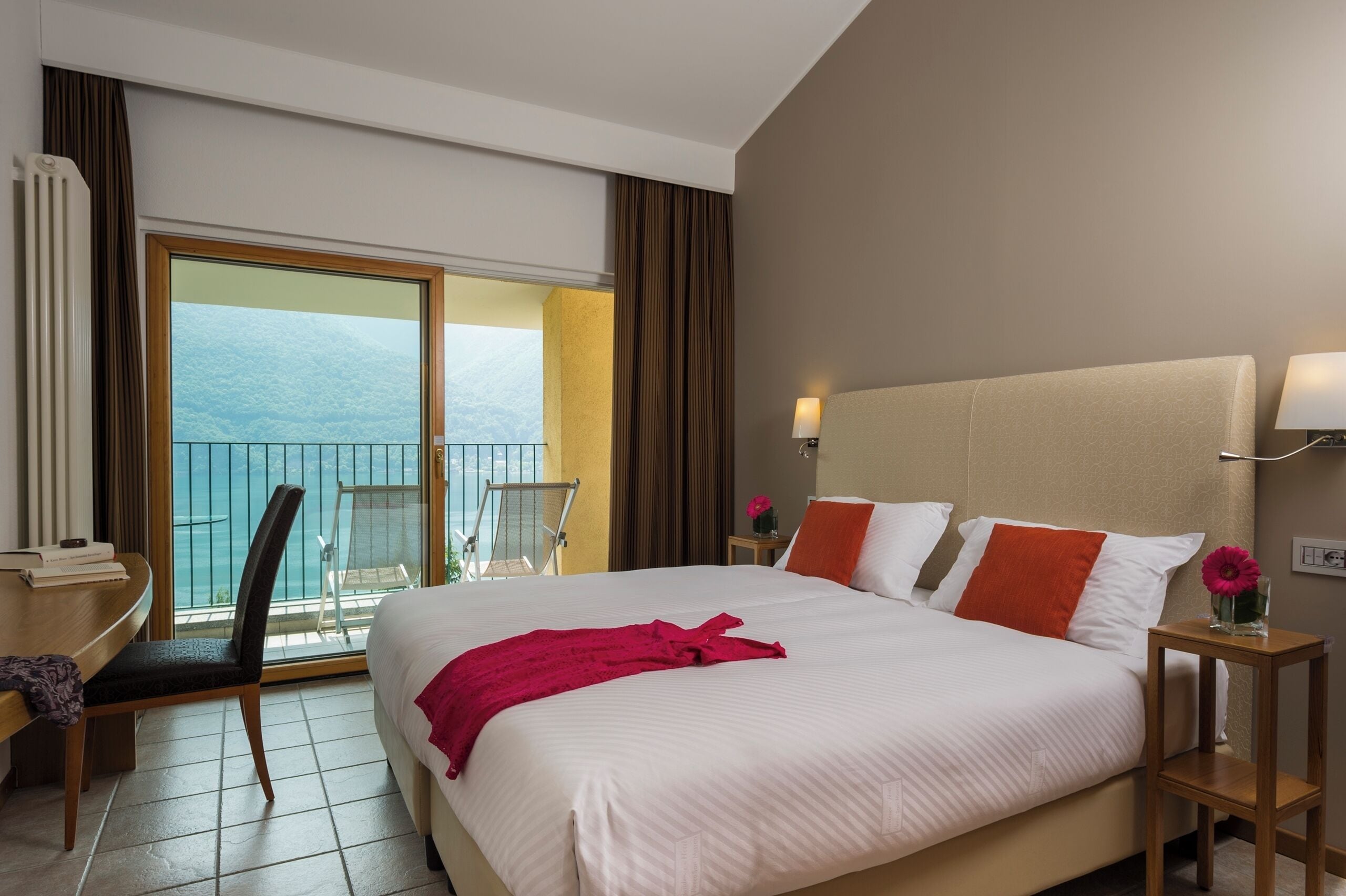Quarto de hotel com uma cama grande, uma mesa, uma cadeira, uma varanda com vista e uma janela.