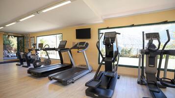 Una palestra con tapis roulant, ellittiche e cyclette, ampie finestre con vista e un pavimento uniforme.