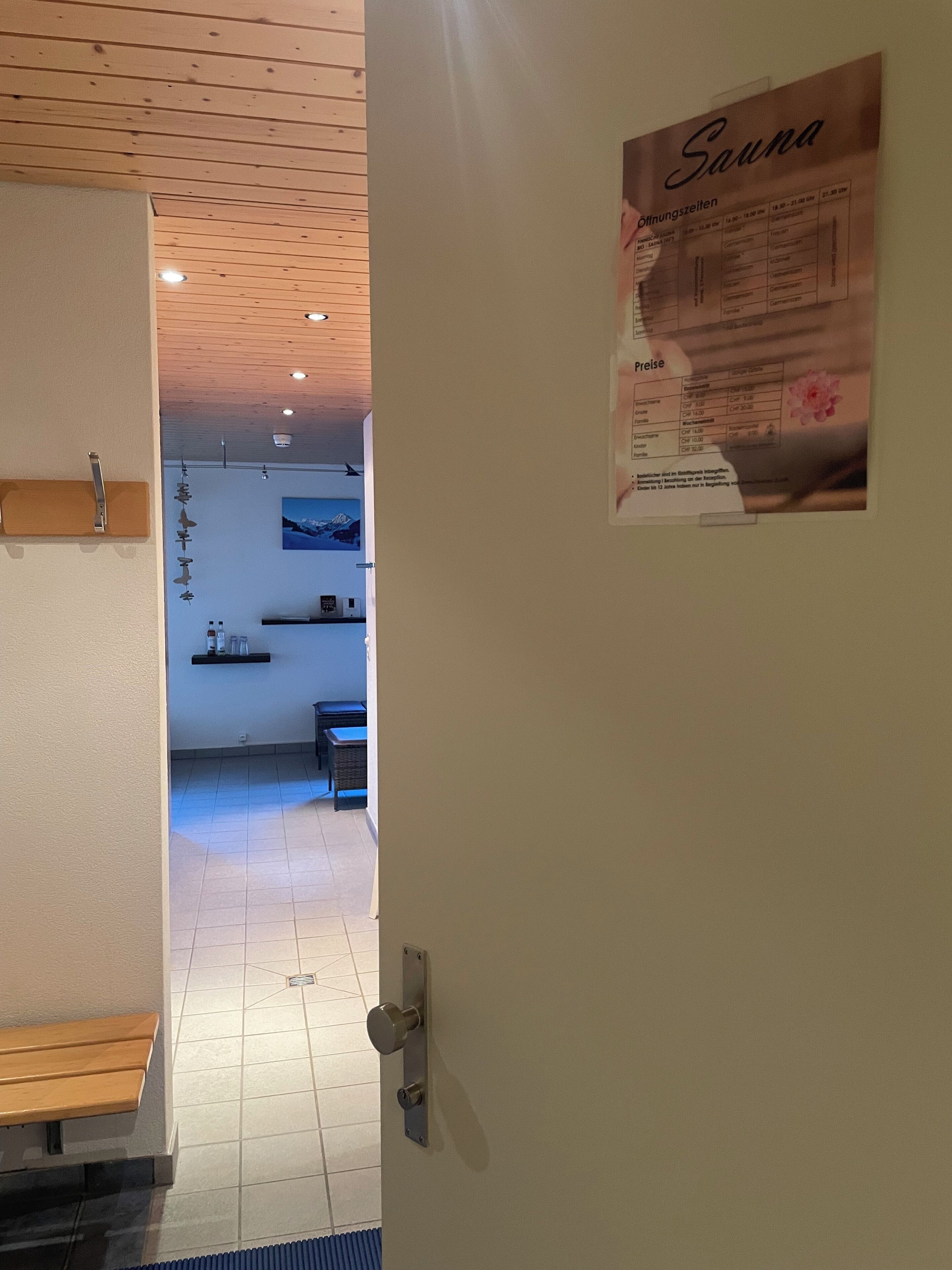Un pasillo con techo de madera, un cartel en la pared y un banco.