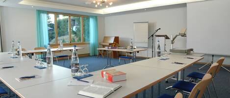 A conference room with a long table, chairs, a piano, and a whiteboard.