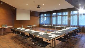 A conference room with long tables, chairs, and a projector screen.