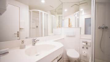 A modern bathroom with a large mirror, a sink, a toilet, and a shower.