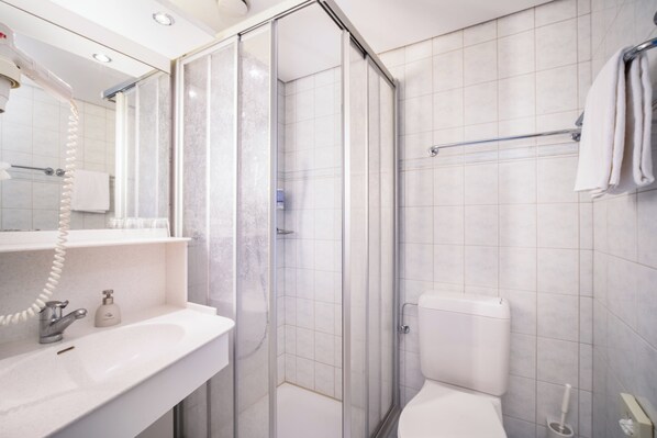 A modern bathroom with a glass-enclosed shower, a white sink, and a toilet. - Seeblick Höhenhotel (Emmetten)