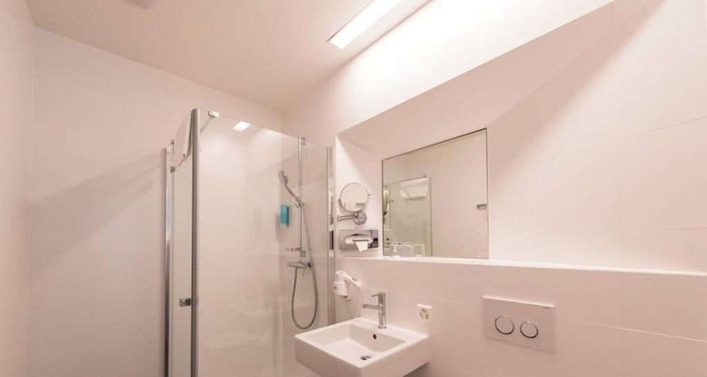 Een moderne badkamer met een douchecabine van glas, een wastafel en een spiegel.