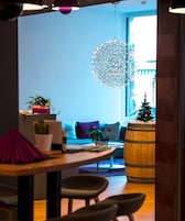 Una sala de estar moderna con un sofá azul, una mesa de centro de madera y una lámpara colgante de diseño geométrico.