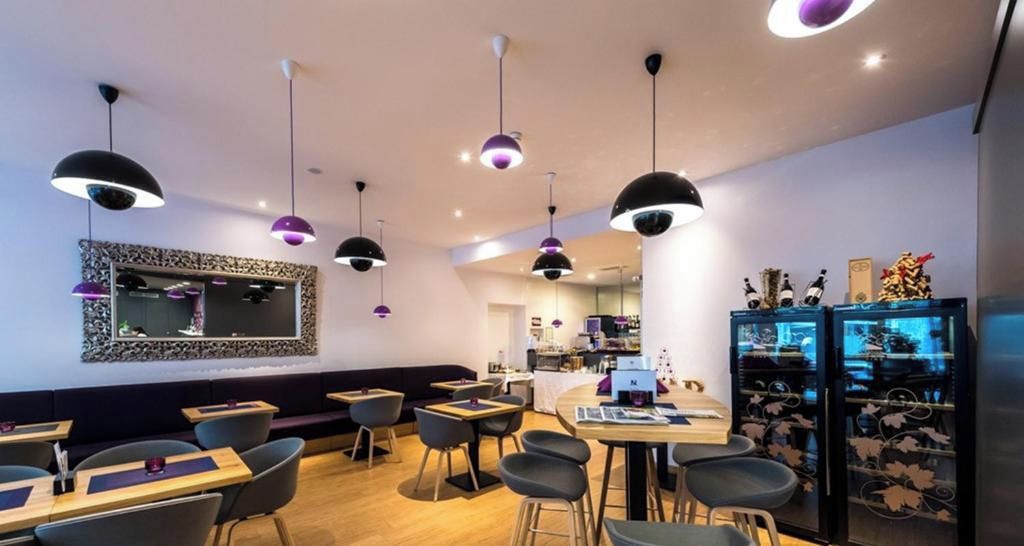 Ein Restaurantinneres mit mehreren Essplätzen, Stühlen, Pendelleuchten, einer Bar und einem Kühlschrank mit Dekoration.