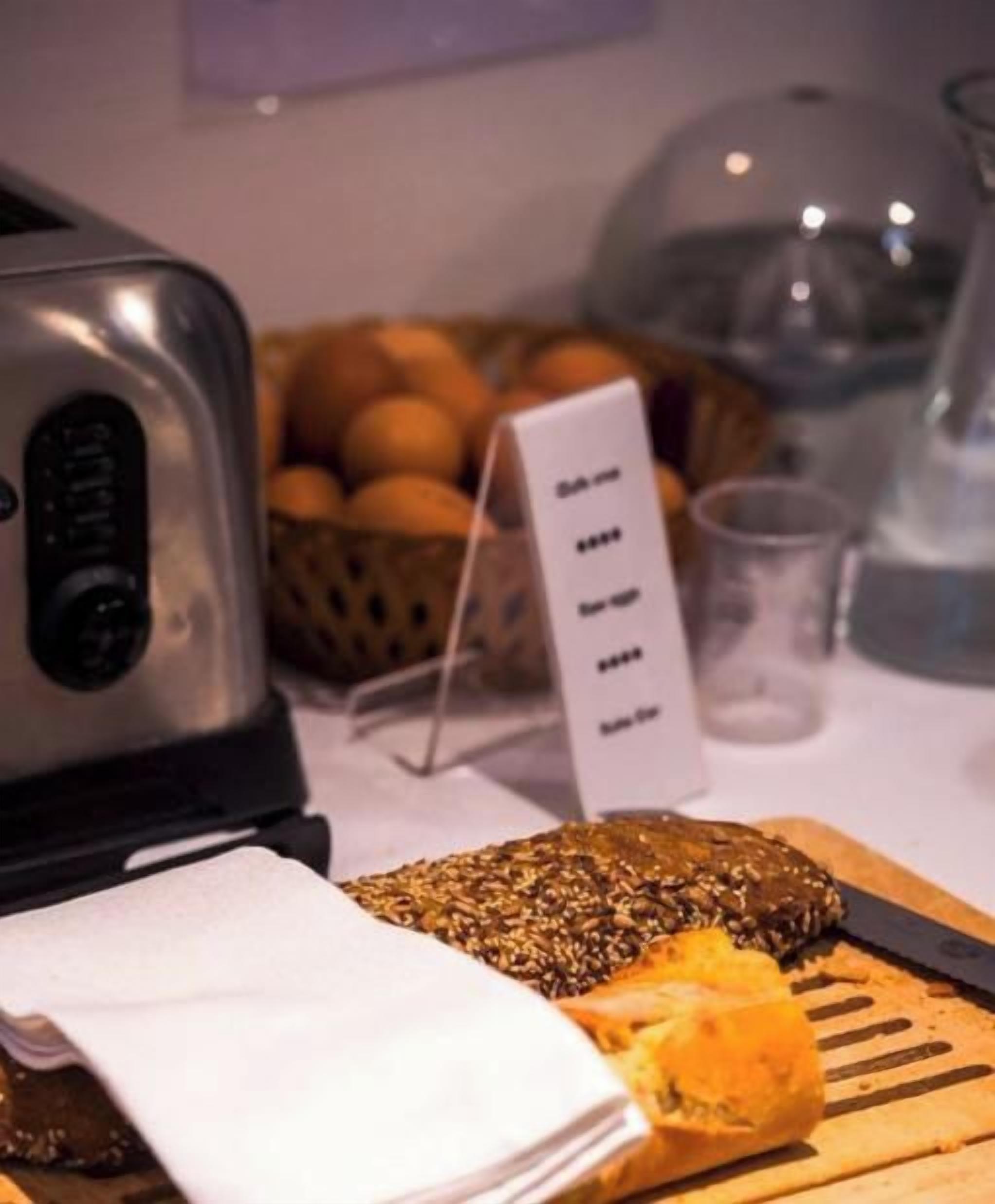 A breakfast setting with a toaster, a basket of oranges, a cutting board with a sliced orange, and a menu sign.