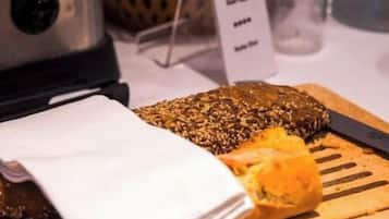 A breakfast setting with a toaster, a basket of oranges, a cutting board with a sliced orange, and a menu sign.