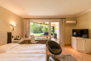 A hotel room with a bed, desk, chair, TV, and a view of the garden. - Albergo Losone (Losone)