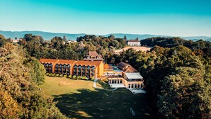 A large hotel with multiple buildings, surrounded by lush greenery and hills in the background. - Hotel La Barcarolle (Prangins)