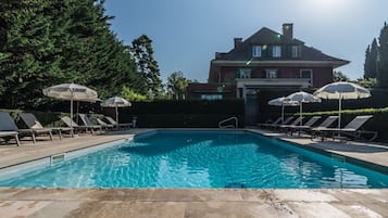 Una piscina al aire libre de temporada, sillones reclinables de piscina