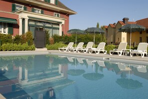 Una piscina al aire libre de temporada, tumbonas