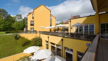 A yellow building with outdoor seating and a balcony.