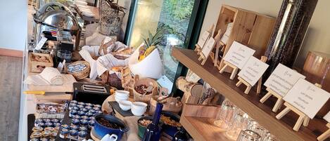 Uma área de buffet com diversos alimentos, bebidas e um canto para café.