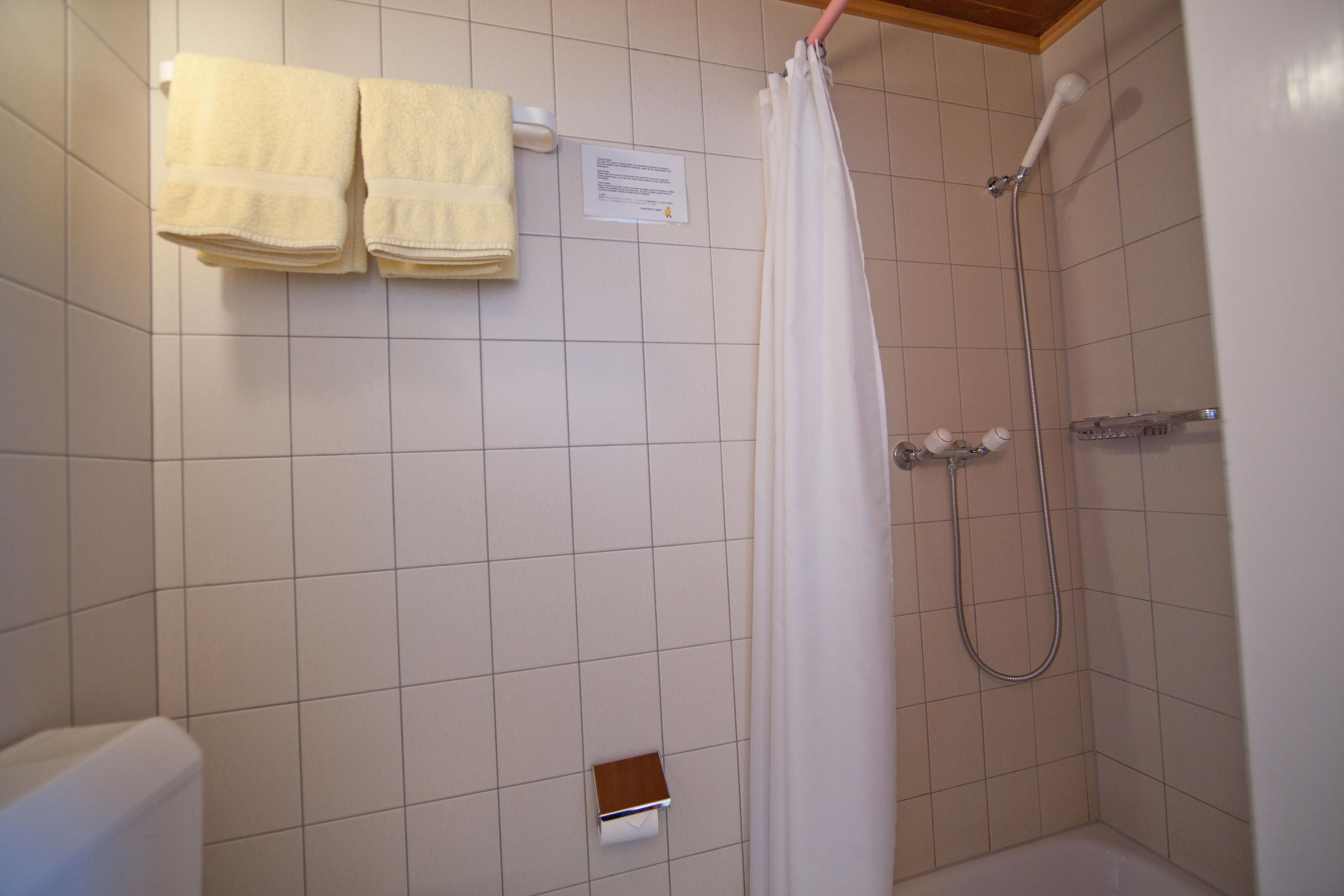 Une salle de bain avec une douche, des toilettes et deux serviettes accrochées au mur.