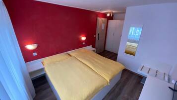 Une petite chambre à coucher moderne, équipée d’un lit, d’une armoire et d’un miroir.