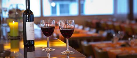 A bar area with a bottle of wine and two glasses of red wine on a reflective surface.