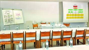 A conference room with a whiteboard displaying a diagram and the words "LOVE & RESPECT", a projector screen with an organizational chart, and tables set with water bottles and glasses.