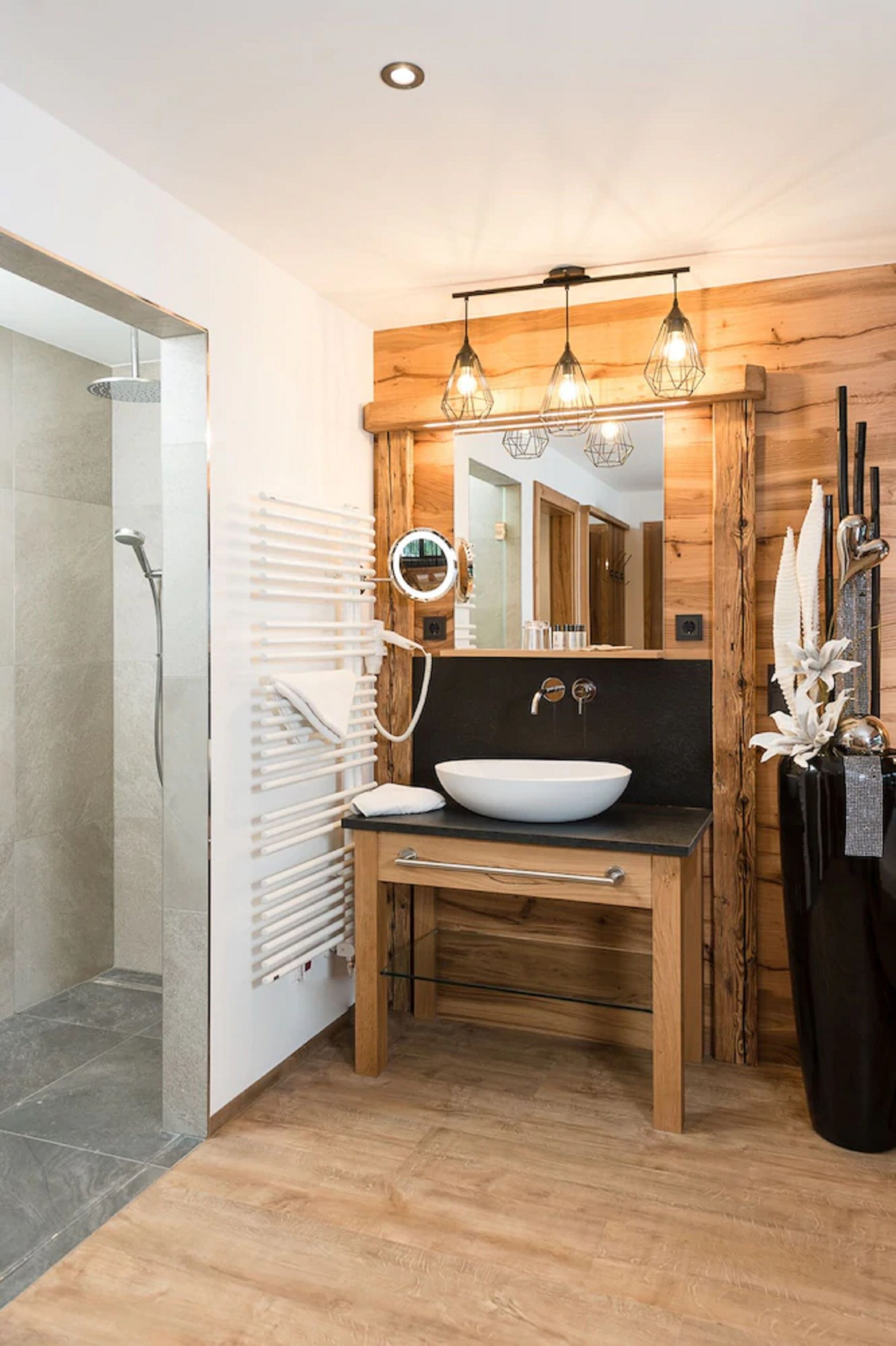 A modern bathroom with a wooden vanity, a large mirror, and a vessel sink.