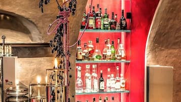 A bar area with a red shelving unit stocked with various liquor bottles, a decorative glass centerpiece, and a sign for Alpenhotel.