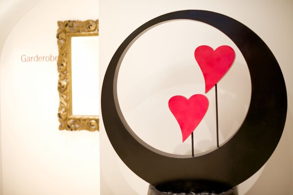 A wall with a gold ornate frame and a circular mirror with two red heart decorations. - Alpenlove - Adult SPA Hotel (Seefeld in Tirol)