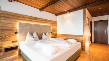 A modern hotel room with a wooden headboard, a large bed with white linens, a bedside lamp, and a wooden floor.