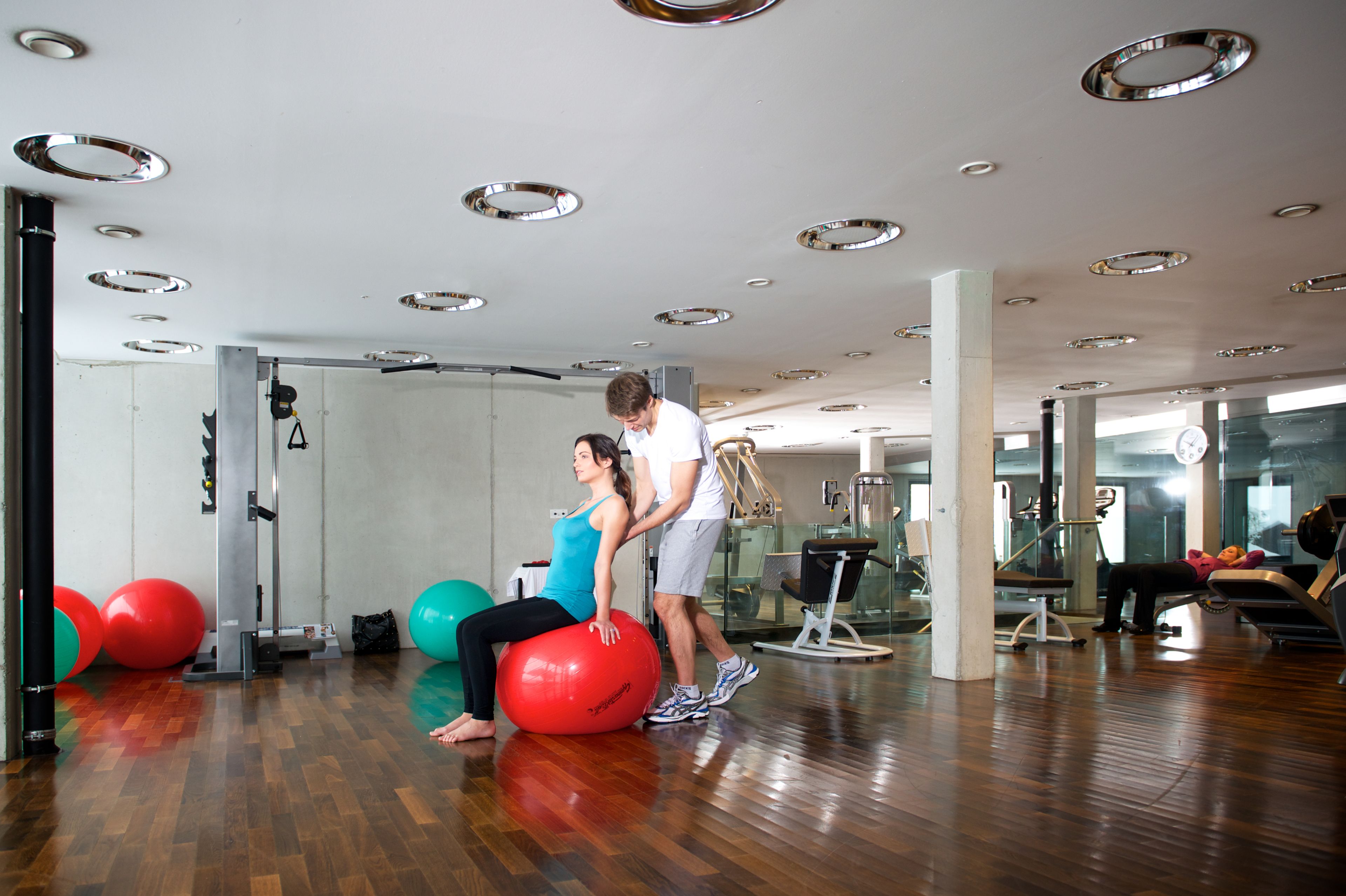 A gym with exercise equipment, wooden floors, and a large mirror.
