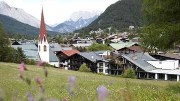 Eine Stadt mit einem markanten Kirchengebäude, Häusern mit schrägen Dächern und einer bergigen Kulisse.