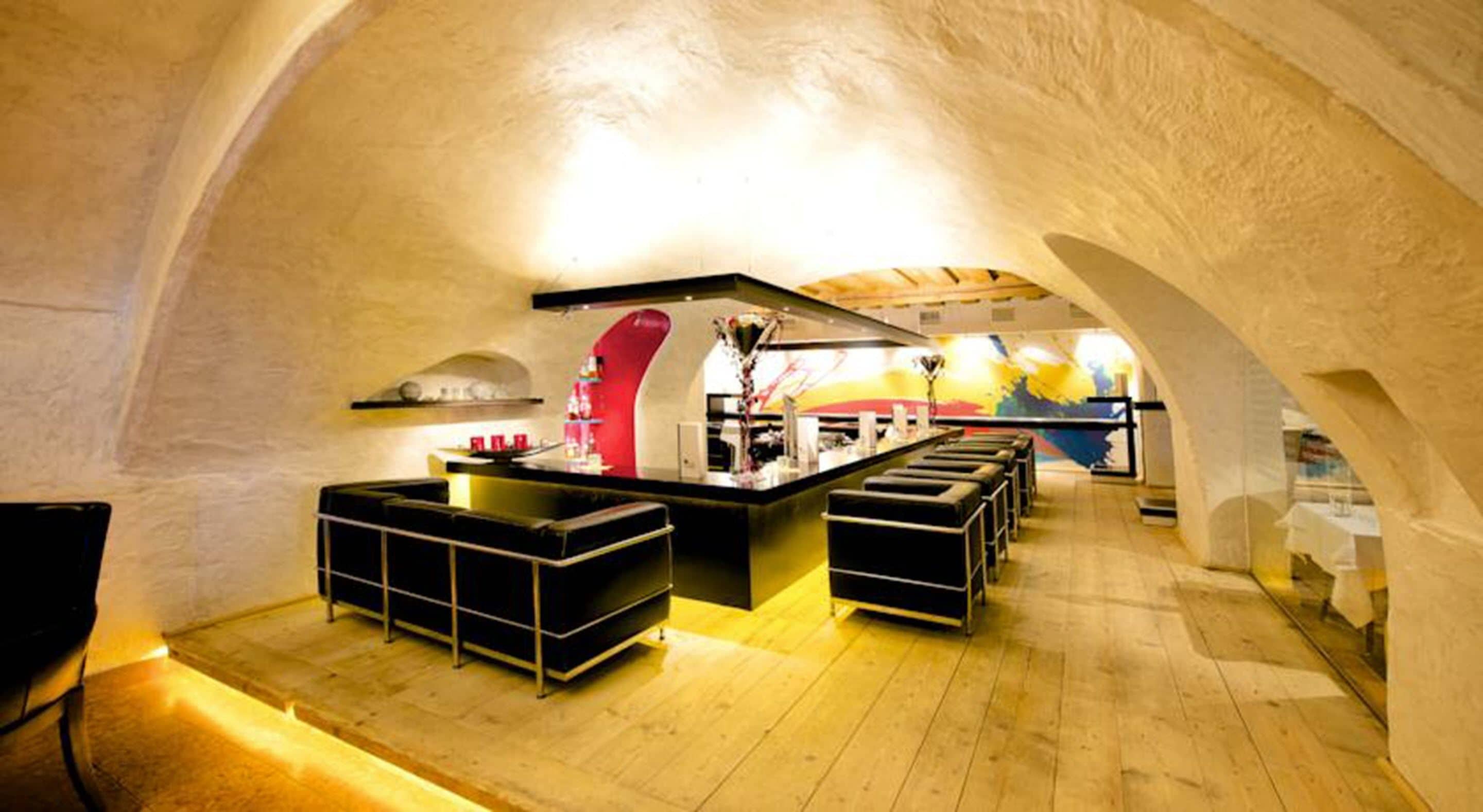 Un interior con barra central, asientos y cocina en una habitación abovedada.