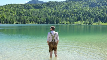 Ein Mann steht im flachen Wasser, im Hintergrund ein bewaldeter Hügel.