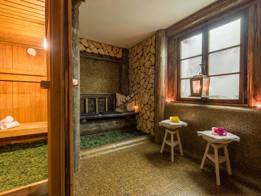 Ein Saunaraum mit Holzbänken, einer Steinwand und einem Fenster mit Milchglas.