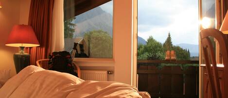 A bedroom with a bed, a window, and a view of mountains.