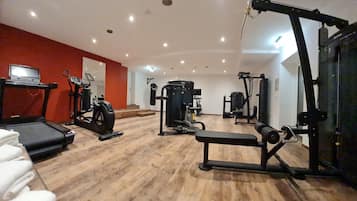Un gimnasio con equipo de ejercicio, una cinta de correr y una banca.