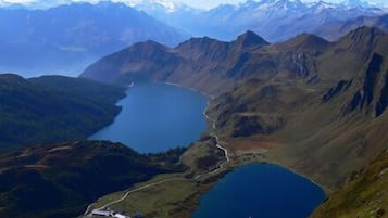 Paisaje montañoso con un lago y un camino sinuoso.
