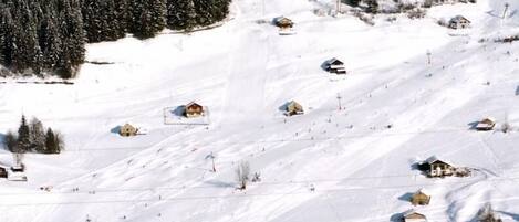 Un pueblo de montaña cubierto de nieve con casas pequeñas y una pista de esquí.