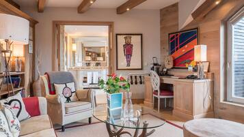 A spacious living room with a glass coffee table, a sofa, and a dining area with a wooden desk and chair.
