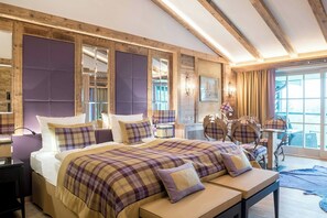 A bedroom with a large bed, a bench, a desk, and a chair. - Alpin Resort Sacher (Seefeld in Tirol)