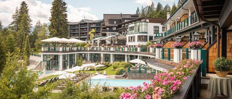 A hotel with a pool, outdoor seating, and a balcony with flowers.