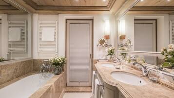 A modern bathroom with a large bathtub, two sinks, and a mirror.