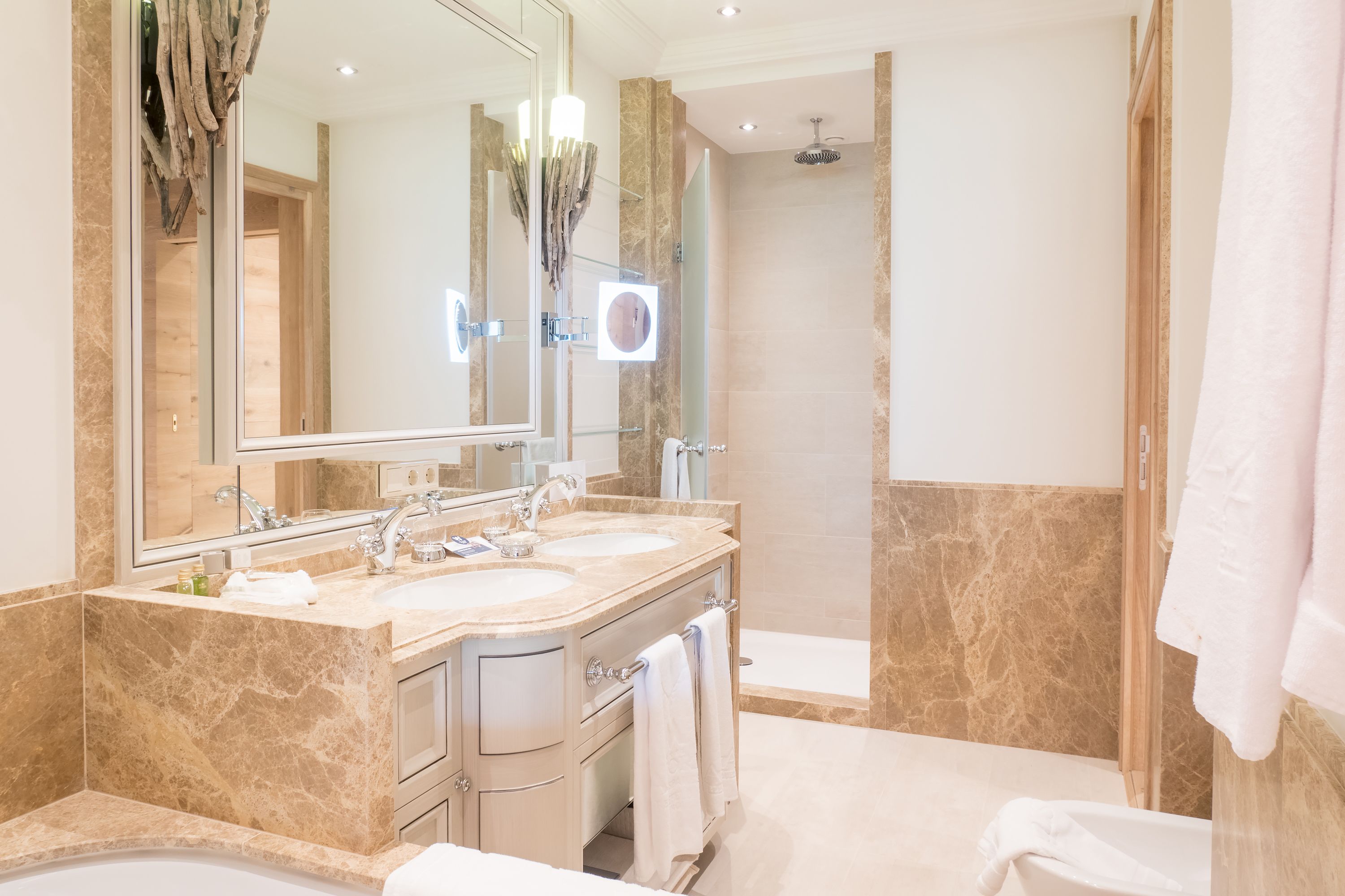 A modern bathroom with two sinks, a large mirror, and a shower.