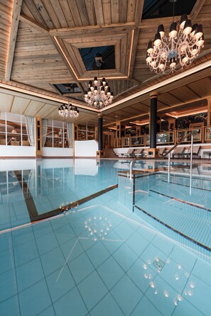 A large indoor swimming pool with wooden beams, chandeliers, and sunlit windows. - Alpin Resort Sacher (Seefeld in Tirol)